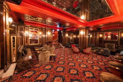 Escalier et couloir décoré de rouge avec fresque murale sculptée, éclairage chaleureux et moquette au sol.