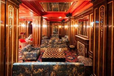 Escalier et couloir décoré de rouge avec fresque murale sculptée, éclairage chaleureux et moquette au sol.