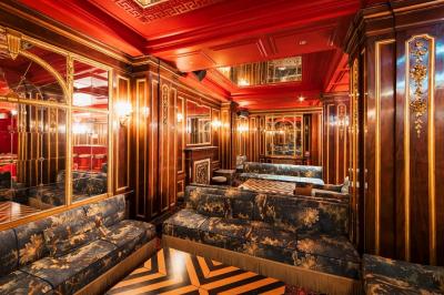 Escalier et couloir décoré de rouge avec fresque murale sculptée, éclairage chaleureux et moquette au sol.