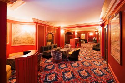 Escalier et couloir décoré de rouge avec fresque murale sculptée, éclairage chaleureux et moquette au sol.