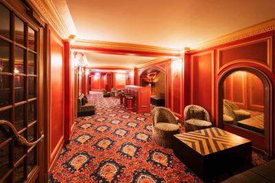 Escalier et couloir décoré de rouge avec fresque murale sculptée, éclairage chaleureux et moquette au sol.