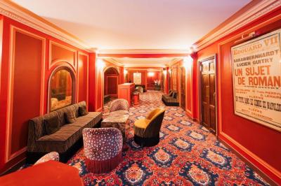 Escalier et couloir décoré de rouge avec fresque murale sculptée, éclairage chaleureux et moquette au sol.