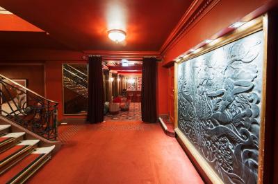 Escalier et couloir décoré de rouge avec fresque murale sculptée, éclairage chaleureux et moquette au sol.