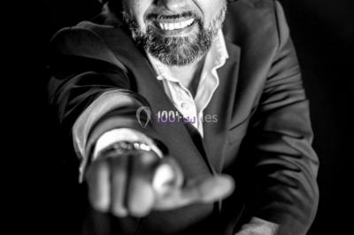 Miniature DJ Champigny-sur-Marne (Val-de-Marne) - Forever Event - DJ Garwell #6 Homme souriant portant un casque audio et un costume sombre, éclairé par une lumière douce sur fond noir.