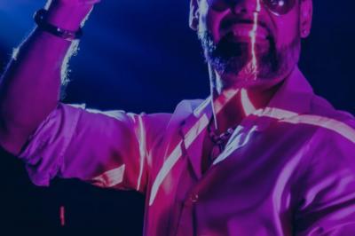 Miniature DJ Champigny-sur-Marne (Val-de-Marne) - Forever Event - DJ Garwell #11 Homme souriant portant un casque audio et un costume sombre, éclairé par une lumière douce sur fond noir.