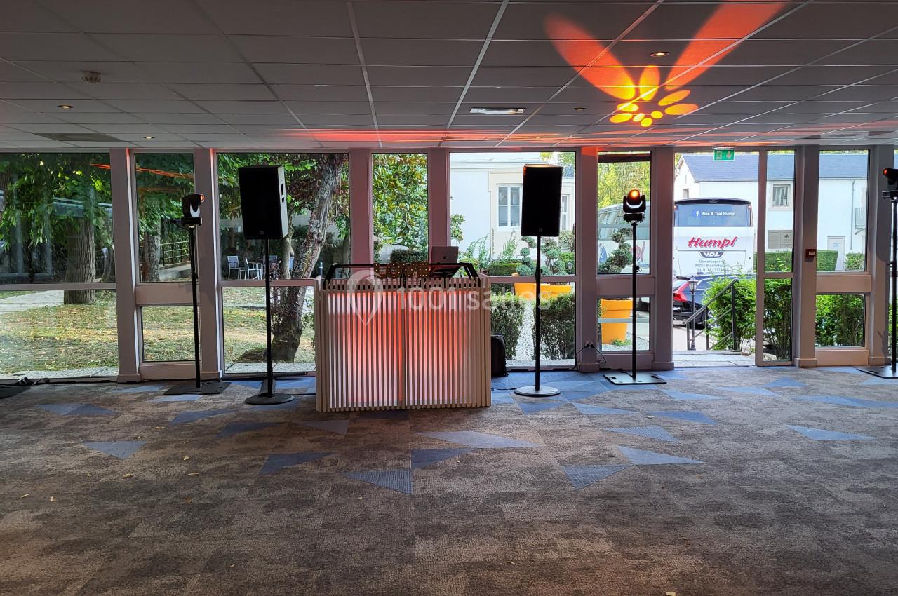 Installation de matériel de sonorisation avec enceintes et éclairages dans une salle vitrée donnant sur un jardin.