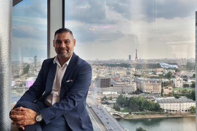 Miniature DJ Champigny-sur-Marne (Val-de-Marne) - Forever Event - DJ Garwell #18 Homme souriant portant un casque audio et un costume sombre, éclairé par une lumière douce sur fond noir.