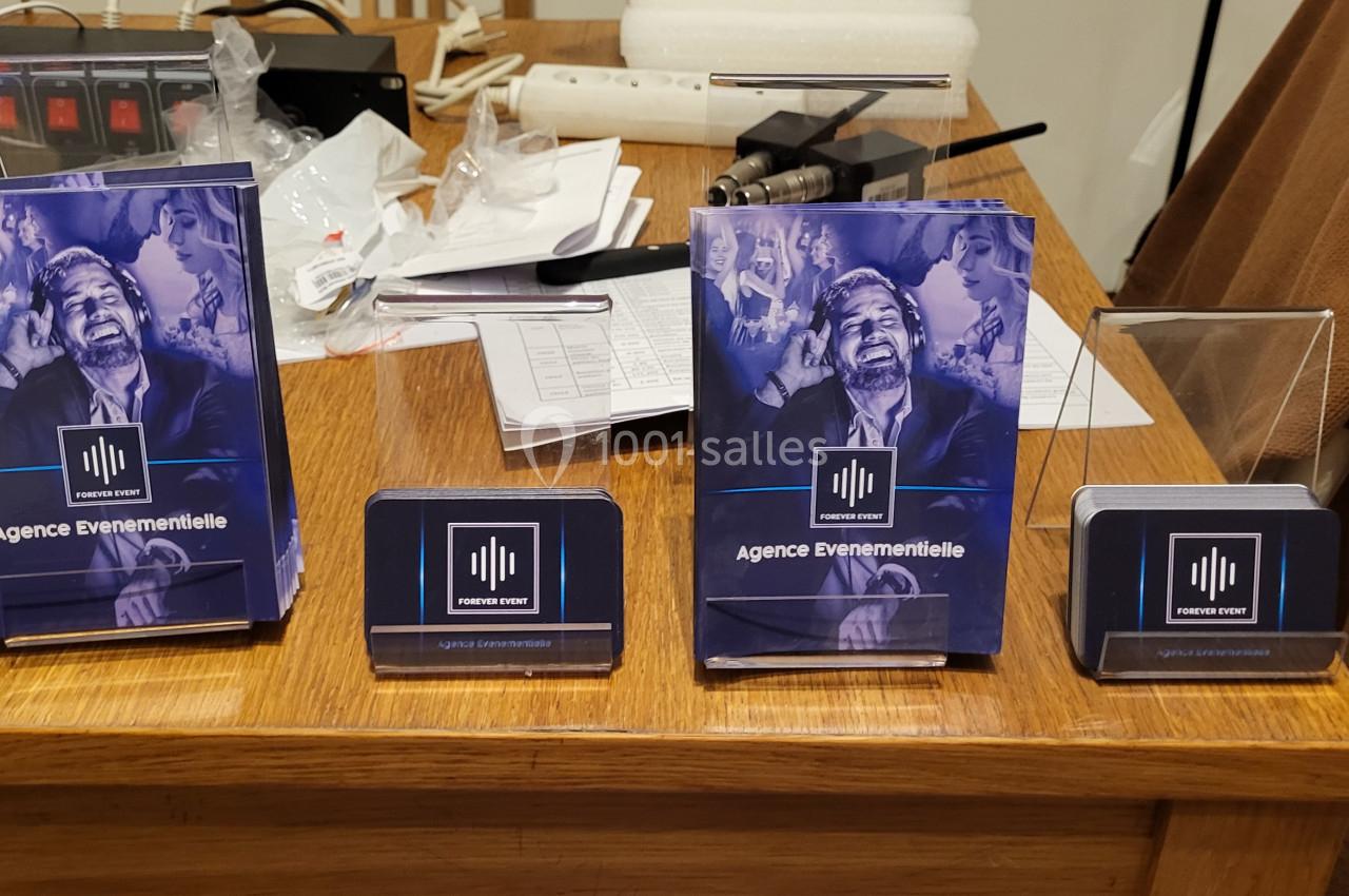 Supports publicitaires d'une agence événementielle disposés sur un bureau en bois, avec des documents en arrière-plan.