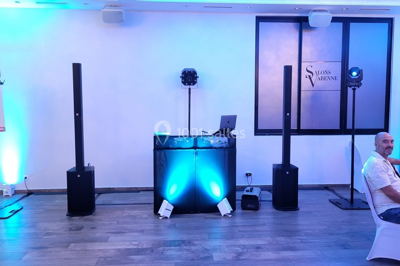 Installation de matériel de sonorisation et d'éclairage dans une salle avec un pupitre lumineux et des enceintes.