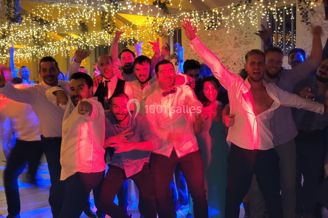 Un groupe de personnes souriantes dansant sous des guirlandes lumineuses dans une salle festive.