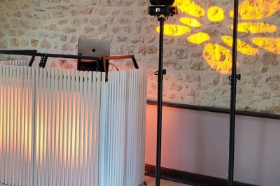 Installation de matériel audiovisuel avec éclairage violet, devant un mur décoré de fleurs blanches.