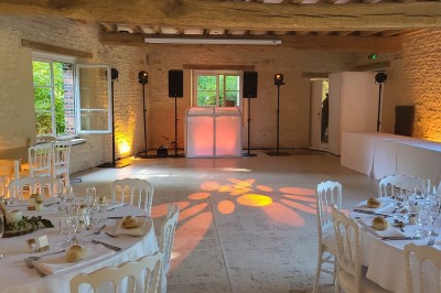 Installation de matériel audiovisuel avec éclairage violet, devant un mur décoré de fleurs blanches.