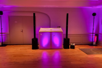 Installation de matériel audiovisuel avec éclairage violet, devant un mur décoré de fleurs blanches.