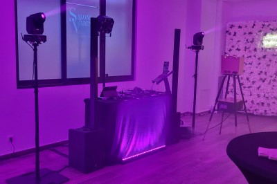 Installation de matériel audiovisuel avec éclairage violet, devant un mur décoré de fleurs blanches.