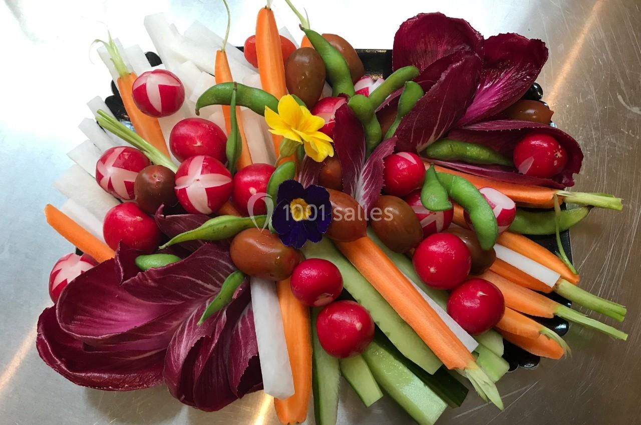 Plateau de crudités colorées avec radis, carottes, céleri, tomates cerises, endives et fleurs comestibles.