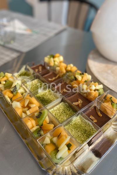 Plateau de verrines variées contenant des fruits frais, mousse au chocolat et crème décorée de pistaches râpées.