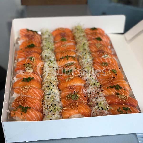 Plateau de sushis au saumon, garnis de graines, herbes fraîches et pousses, présenté dans une boîte blanche.