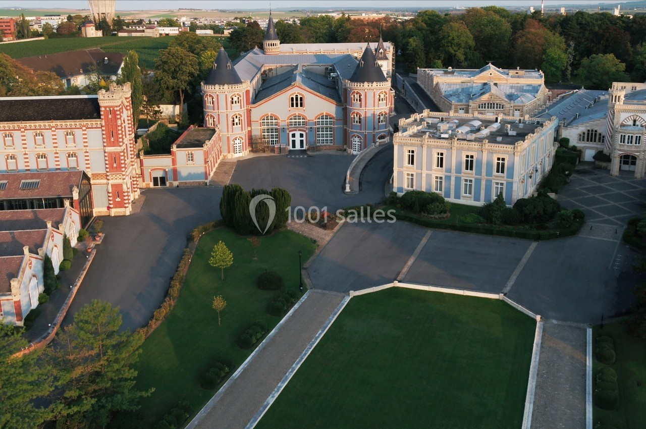 Vue aérienne d'un domaine avec plusieurs bâtiments historiques entourés de jardins et de végétation.