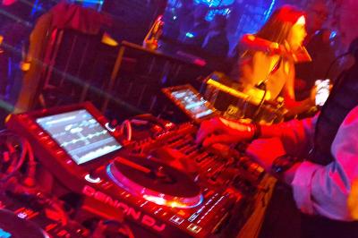 Un DJ mixe sur scène dans une ambiance sombre et lumineuse, décorée avec des éléments d'Halloween.