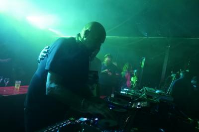 Un DJ mixe sur scène dans une ambiance sombre et lumineuse, décorée avec des éléments d'Halloween.