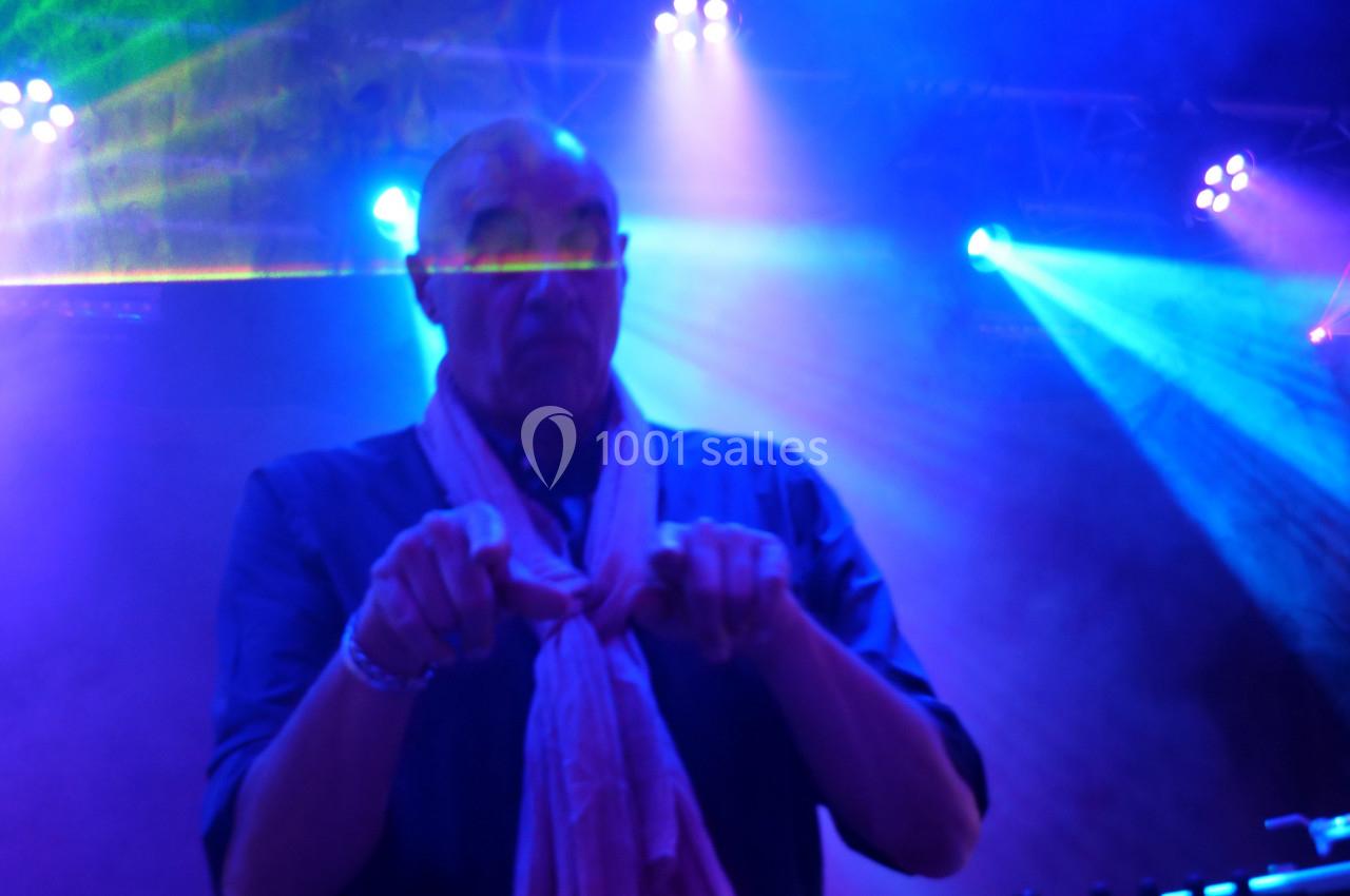 Un DJ mixant sur scène sous des éclairages colorés et des effets de lumière.