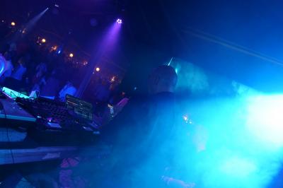 Un DJ mixe sur scène dans une ambiance sombre et lumineuse, décorée avec des éléments d'Halloween.