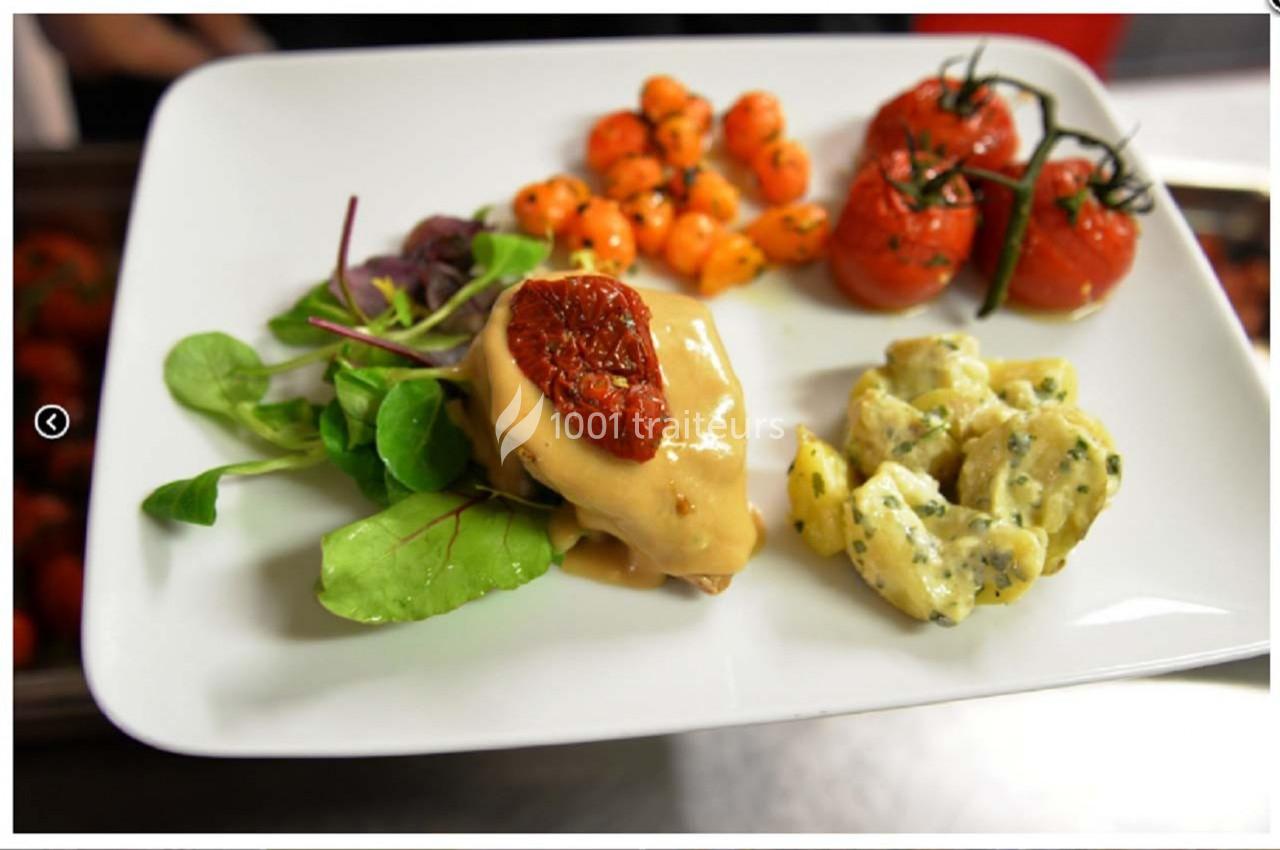 Assiette garnie de légumes grillés, salade verte, viande avec sauce et tomate séchée, accompagnée de pommes de terre.