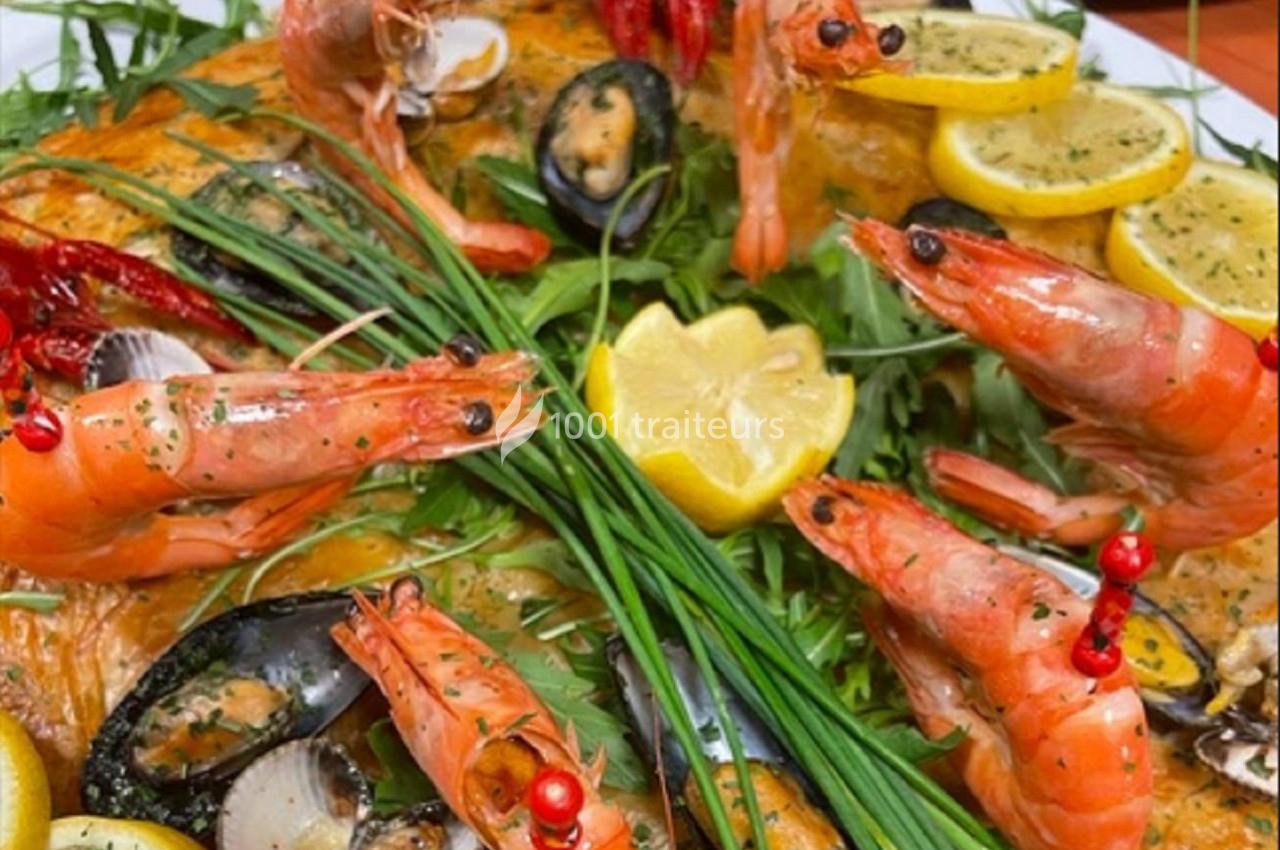 Plat de fruits de mer composé de crevettes, moules, citron, herbes fraîches et légumes sur un lit de salade.