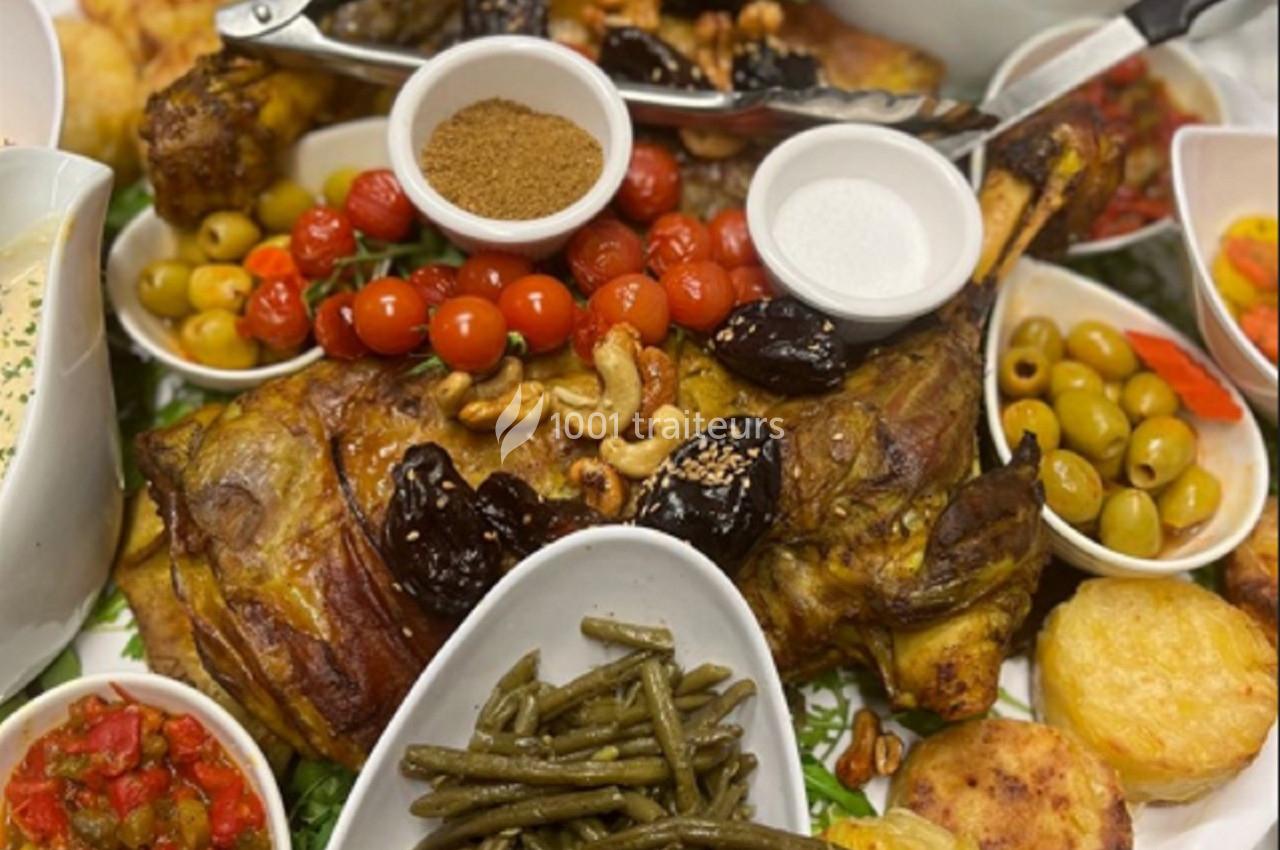 Plat de viande rôtie entouré de légumes, olives, tomates cerises, pruneaux, noix et accompagnements variés.