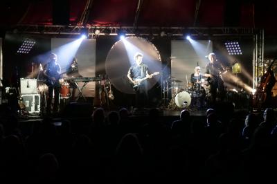 Un bus stationné de nuit devant un bâtiment illuminé, avec des passants en arrière-plan.