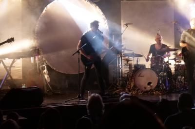Un bus stationné de nuit devant un bâtiment illuminé, avec des passants en arrière-plan.