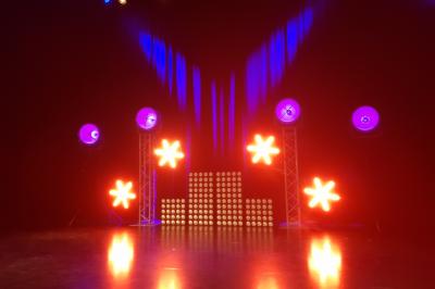 Un bus stationné de nuit devant un bâtiment illuminé, avec des passants en arrière-plan.