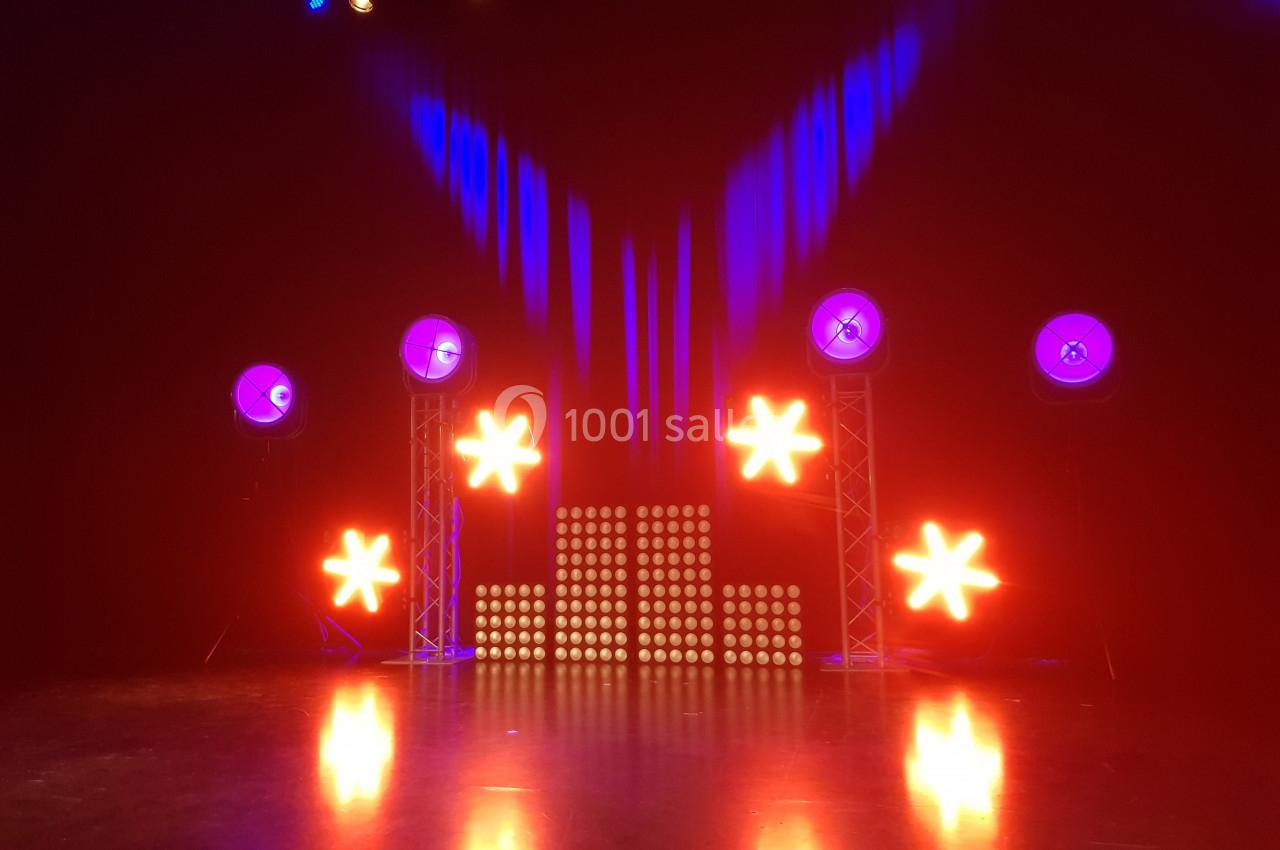 Éclairage de scène avec projecteurs rouges et bleus, étoiles lumineuses et panneaux LED sur fond sombre.