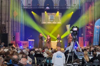Un bus stationné de nuit devant un bâtiment illuminé, avec des passants en arrière-plan.