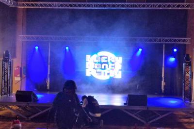 Un bus stationné de nuit devant un bâtiment illuminé, avec des passants en arrière-plan.