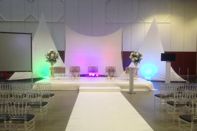 Un bus stationné de nuit devant un bâtiment illuminé, avec des passants en arrière-plan.