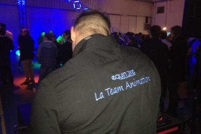 Un bus stationné de nuit devant un bâtiment illuminé, avec des passants en arrière-plan.