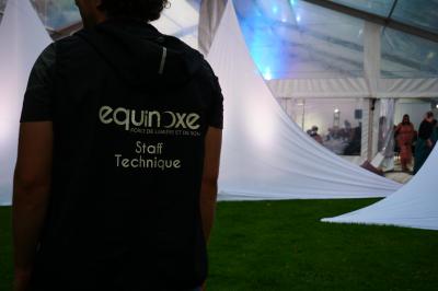 Un bus stationné de nuit devant un bâtiment illuminé, avec des passants en arrière-plan.