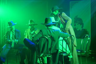 Un bus stationné de nuit devant un bâtiment illuminé, avec des passants en arrière-plan.