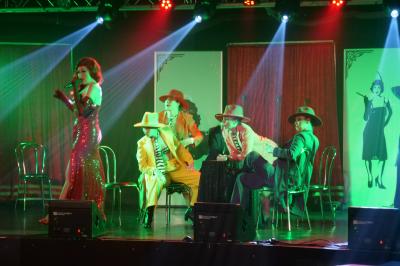 Un bus stationné de nuit devant un bâtiment illuminé, avec des passants en arrière-plan.