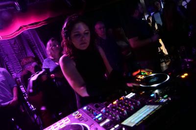 Un bus stationné de nuit devant un bâtiment illuminé, avec des passants en arrière-plan.