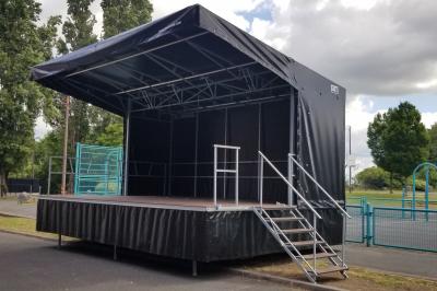 Un bus stationné de nuit devant un bâtiment illuminé, avec des passants en arrière-plan.