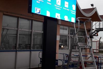 Un bus stationné de nuit devant un bâtiment illuminé, avec des passants en arrière-plan.