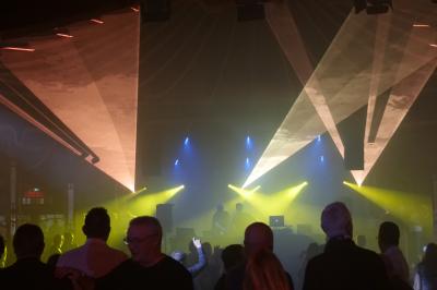 Un bus stationné de nuit devant un bâtiment illuminé, avec des passants en arrière-plan.