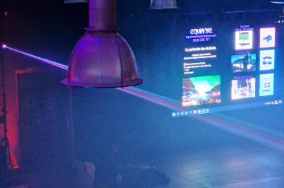 Un bus stationné de nuit devant un bâtiment illuminé, avec des passants en arrière-plan.