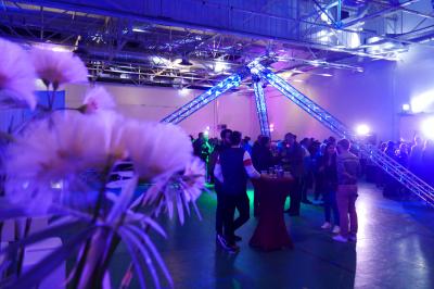Un bus stationné de nuit devant un bâtiment illuminé, avec des passants en arrière-plan.