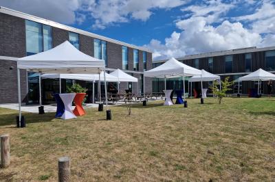 Un bus stationné de nuit devant un bâtiment illuminé, avec des passants en arrière-plan.