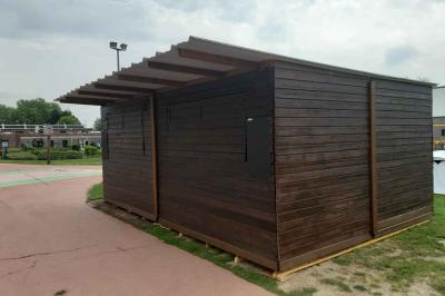 Un bus stationné de nuit devant un bâtiment illuminé, avec des passants en arrière-plan.