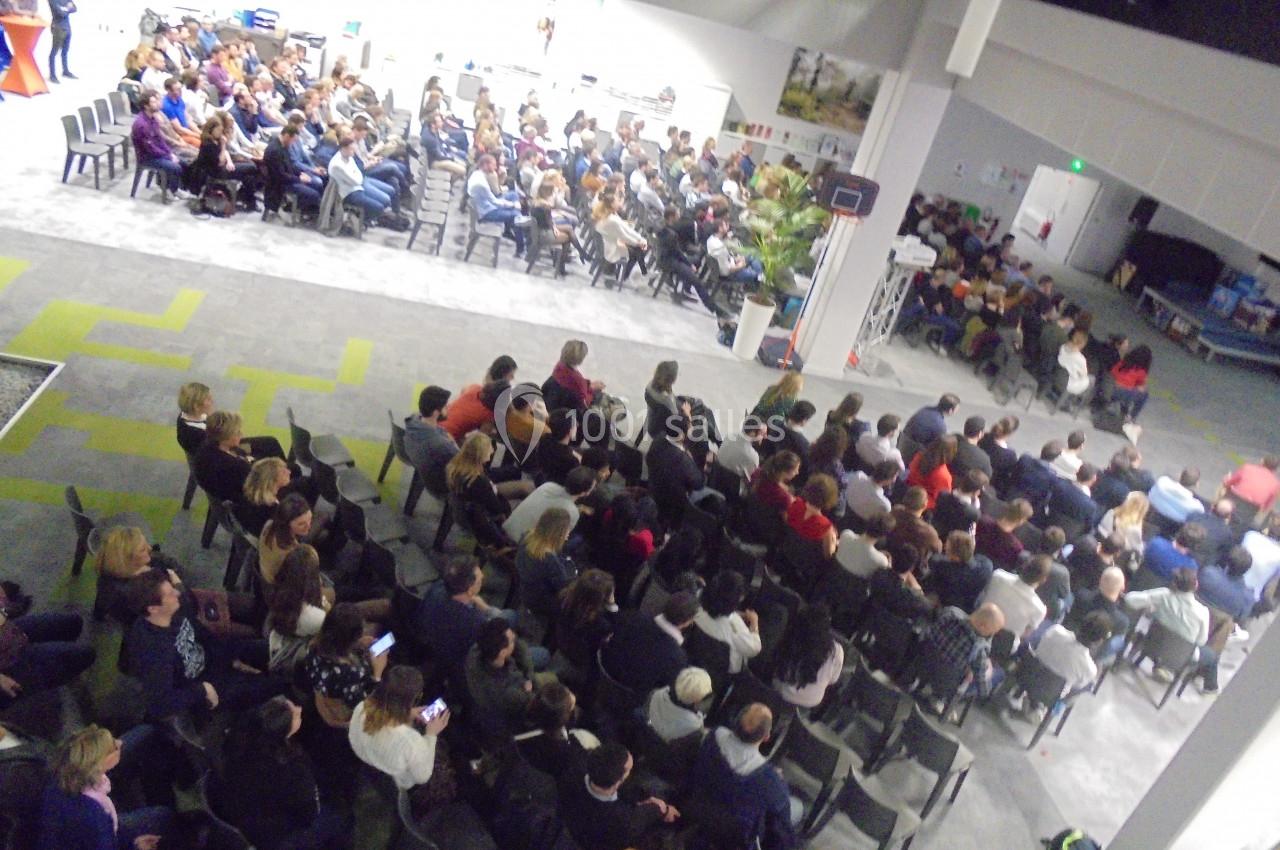 Vue aérienne d'une salle remplie de personnes assises, assistant à une conférence ou un événement collectif.