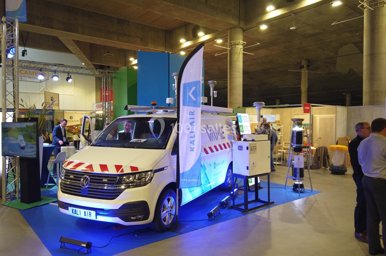 Un véhicule équipé de capteurs et d'appareils de mesure exposé dans un salon professionnel sous un éclairage artificiel.